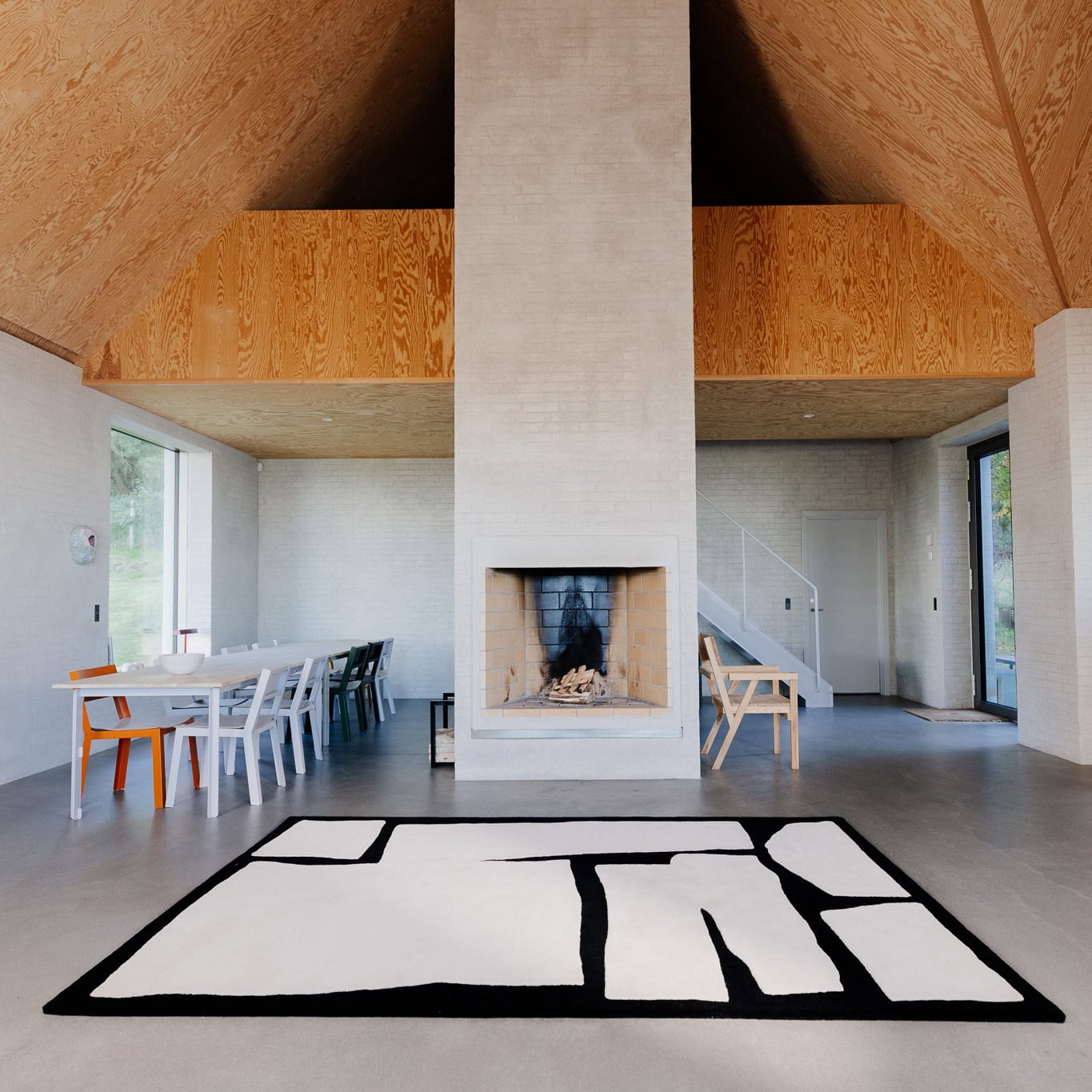 Modern open-plan dining room featuring a stylish black-and-white acoustic rug, designed to enhance soundproofing and reduce echoes."