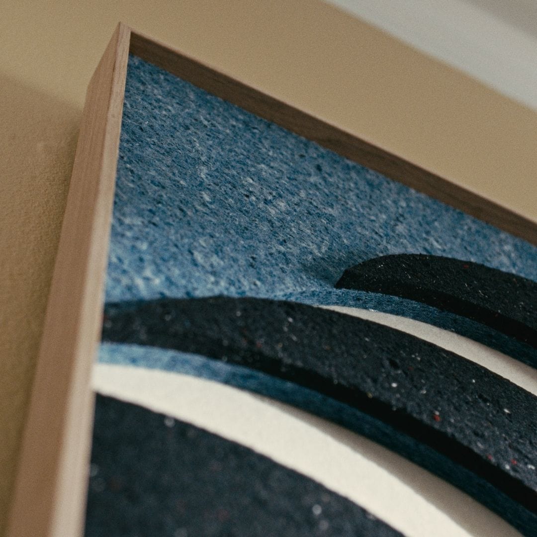 Close-up of acoustic wall panel art in layered blue and black tones with a natural wood frame, enhancing sound absorption.